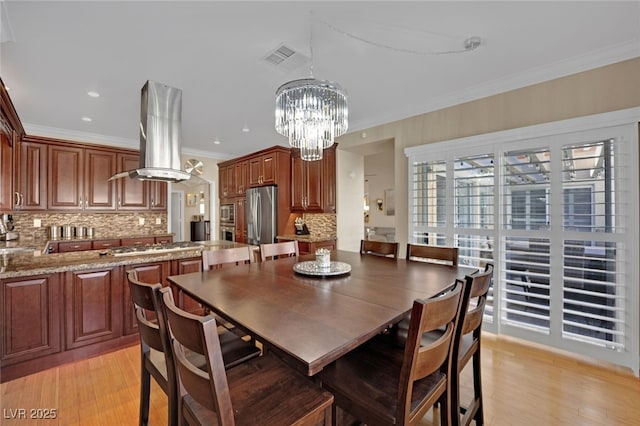 dining room featuring crown molding, a chandelier, and light wood-type flooring