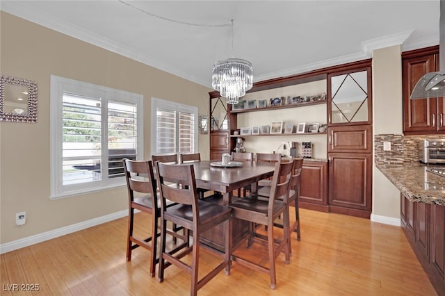 dining room featuring crown molding, a notable chandelier, and light wood-type flooring