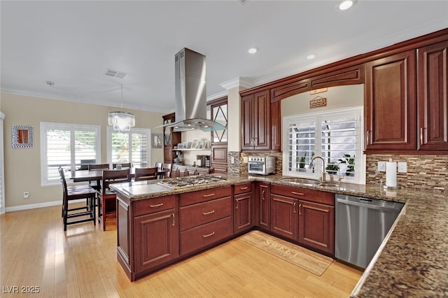 kitchen featuring sink, hanging light fixtures, island exhaust hood, kitchen peninsula, and stainless steel appliances