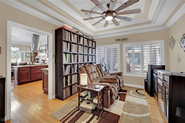 sitting room with a tray ceiling, ornamental molding, light hardwood / wood-style floors, and ceiling fan