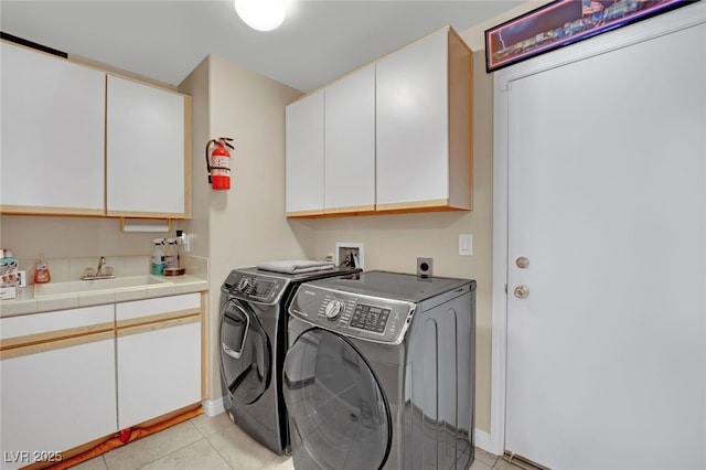 laundry area featuring sink, washer and clothes dryer, cabinets, and light tile patterned flooring