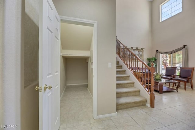 stairs featuring tile patterned flooring and a towering ceiling