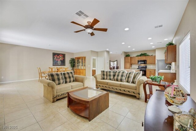 living room with ceiling fan, sink, and light tile patterned floors