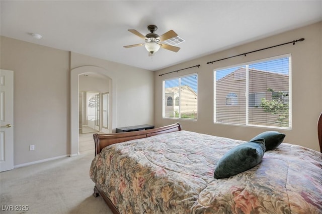 bedroom with ceiling fan, light colored carpet, and ensuite bathroom