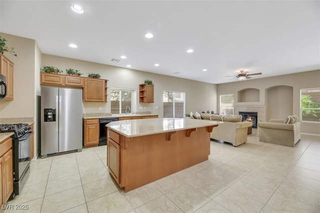 kitchen featuring ceiling fan, a center island, sink, a kitchen bar, and black appliances