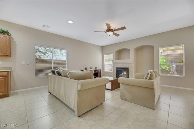 living room with light tile patterned flooring, a wealth of natural light, and a tiled fireplace