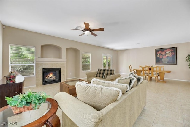 living room with a tiled fireplace, ceiling fan, plenty of natural light, and light tile patterned floors