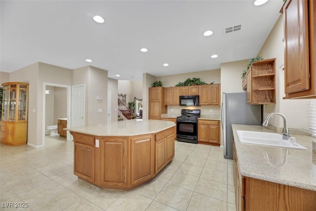 kitchen featuring sink, a kitchen island, light stone counters, light tile patterned flooring, and black appliances