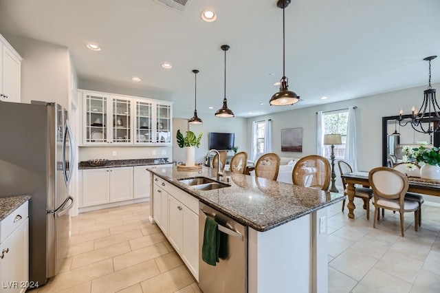 kitchen featuring a kitchen island with sink, white cabinets, sink, dark stone countertops, and stainless steel appliances