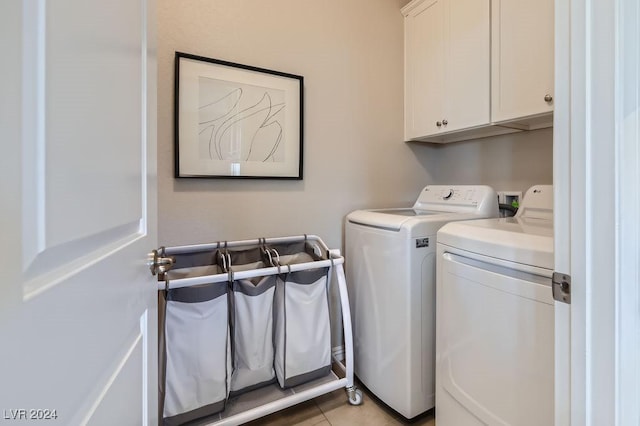 laundry area featuring washer and dryer, light tile patterned floors, and cabinets