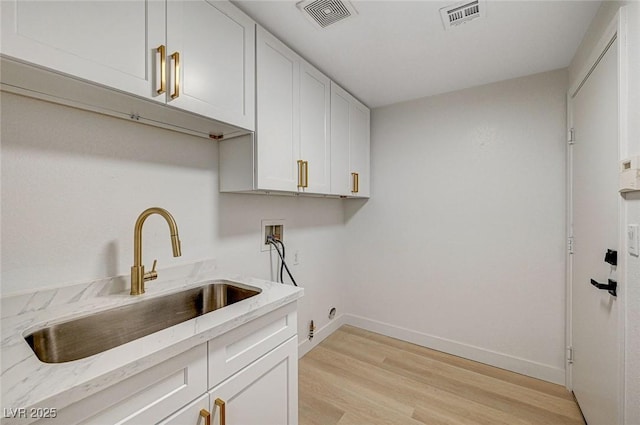 laundry area with sink, cabinets, washer hookup, electric dryer hookup, and light hardwood / wood-style flooring