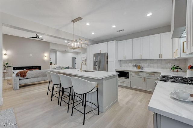 kitchen with a center island, white cabinets, stainless steel refrigerator with ice dispenser, tasteful backsplash, and decorative light fixtures