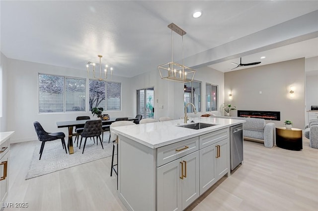 kitchen with ceiling fan, dishwasher, sink, pendant lighting, and a center island with sink