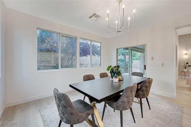 dining space featuring light hardwood / wood-style flooring and a chandelier