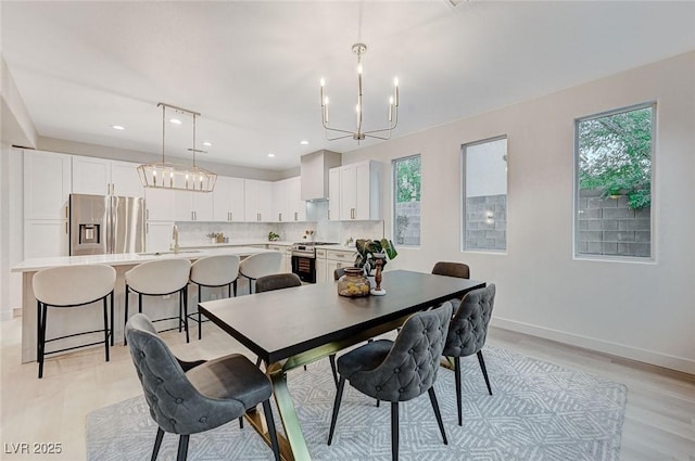 dining room featuring a notable chandelier, plenty of natural light, light hardwood / wood-style floors, and sink