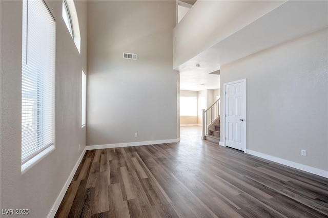 empty room with dark wood-type flooring and a high ceiling