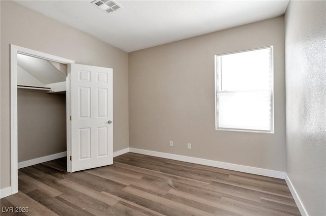 unfurnished bedroom with vaulted ceiling, a closet, and dark hardwood / wood-style floors