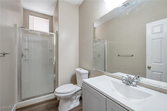 bathroom featuring vanity, wood-type flooring, an enclosed shower, and toilet