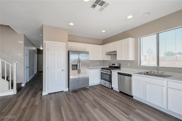 kitchen with appliances with stainless steel finishes, white cabinetry, dark wood-type flooring, and sink