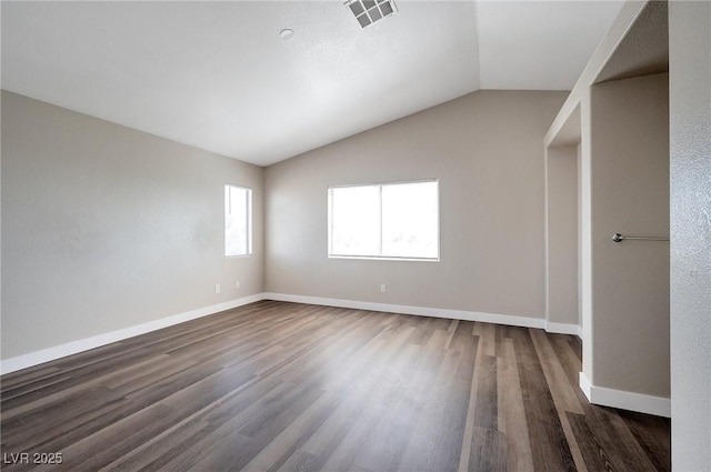 spare room featuring dark wood-type flooring, plenty of natural light, and lofted ceiling