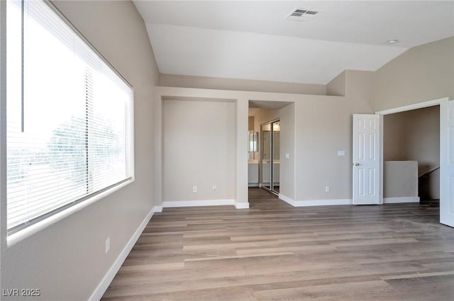 spare room with light hardwood / wood-style floors and lofted ceiling