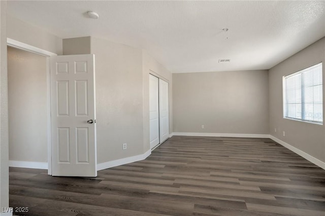 spare room with a textured ceiling and dark hardwood / wood-style floors