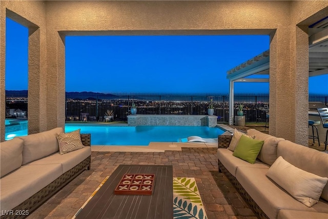 pool at dusk featuring a patio area, pool water feature, and an outdoor hangout area