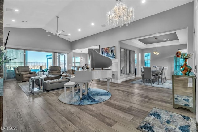 living room featuring hardwood / wood-style floors, ceiling fan with notable chandelier, and a high ceiling