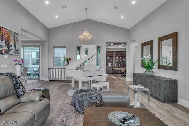 living room featuring radiator heating unit, high vaulted ceiling, light hardwood / wood-style flooring, and a notable chandelier