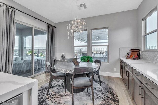 dining space with light hardwood / wood-style flooring, an inviting chandelier, and a wealth of natural light