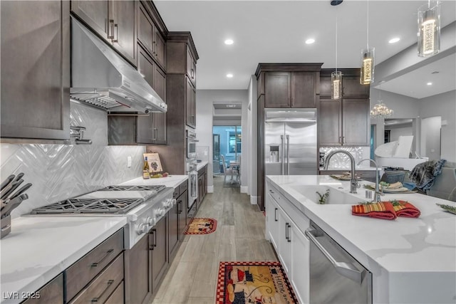 kitchen with pendant lighting, sink, decorative backsplash, light hardwood / wood-style floors, and stainless steel appliances