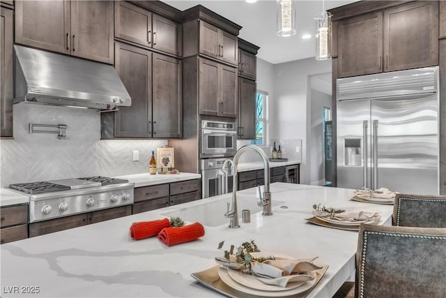 kitchen featuring sink, stainless steel appliances, decorative light fixtures, decorative backsplash, and dark brown cabinets