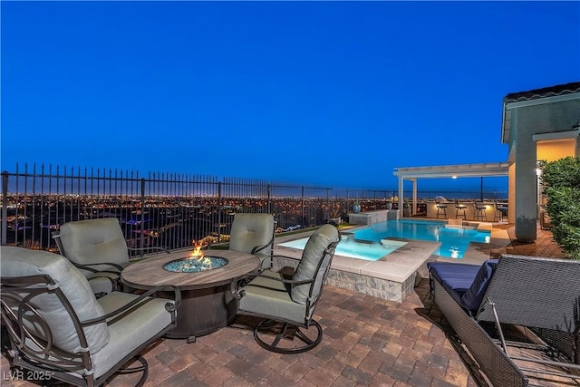 patio terrace at dusk with a swimming pool with hot tub and a fire pit