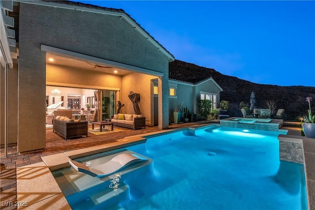 view of pool with an in ground hot tub, outdoor lounge area, a patio area, and a mountain view