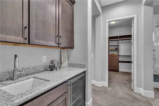 interior space featuring light stone countertops, sink, beverage cooler, and light carpet