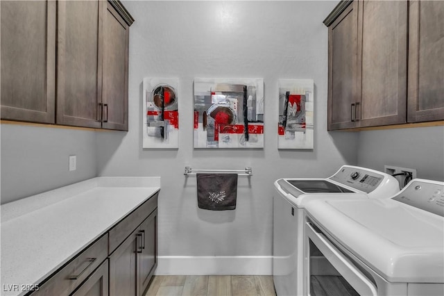 clothes washing area with separate washer and dryer, cabinets, and light wood-type flooring