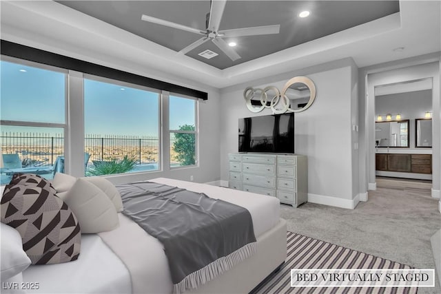 carpeted bedroom with access to exterior, a tray ceiling, ensuite bath, and ceiling fan