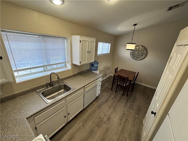 kitchen featuring white dishwasher, vaulted ceiling, sink, decorative light fixtures, and white cabinets