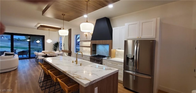 kitchen with wooden ceiling, a kitchen island with sink, white cabinets, decorative light fixtures, and stainless steel appliances