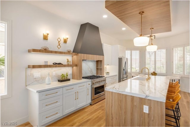 kitchen featuring white cabinets, sink, appliances with stainless steel finishes, decorative light fixtures, and extractor fan