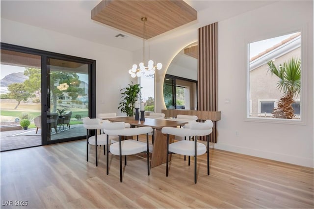 dining room featuring a chandelier, a raised ceiling, light hardwood / wood-style flooring, and wood ceiling