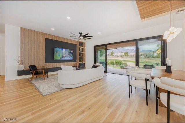 living room with ceiling fan, light hardwood / wood-style flooring, and built in features