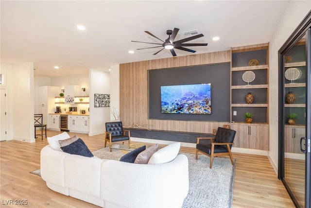 living room with built in features, light hardwood / wood-style floors, wine cooler, and ceiling fan