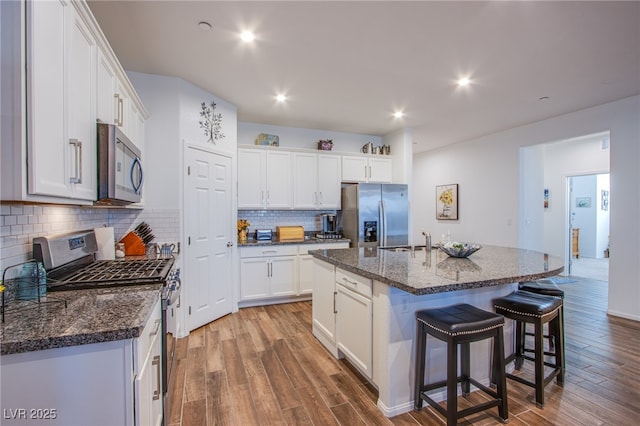 kitchen featuring a kitchen island with sink, sink, white cabinets, and appliances with stainless steel finishes