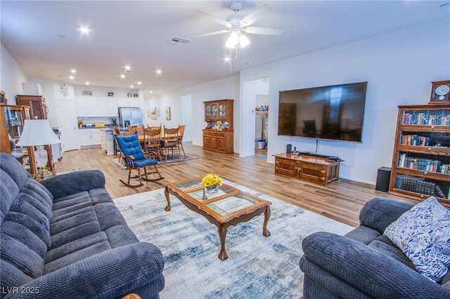 living room featuring ceiling fan and light hardwood / wood-style floors