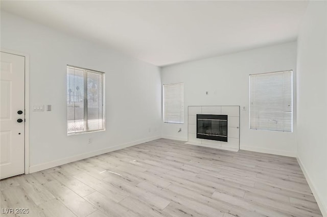 unfurnished living room with light wood-type flooring and a tiled fireplace