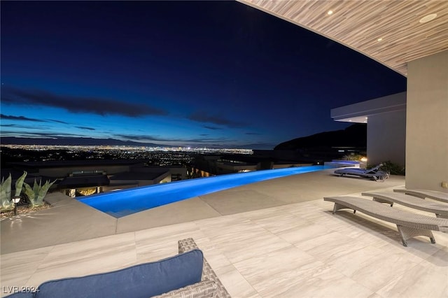 pool at dusk with a patio area