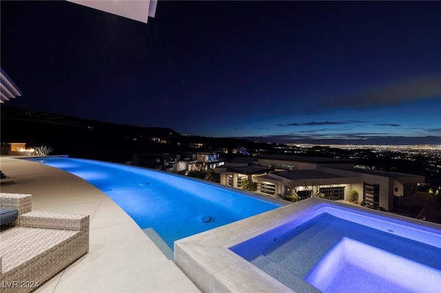 pool at night with an in ground hot tub