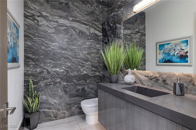 bathroom with tile patterned flooring, vanity, tile walls, and toilet