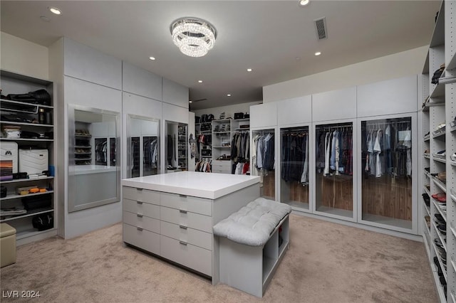 walk in closet featuring light carpet and a chandelier